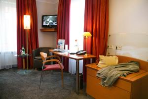 a hotel room with a desk and a bed and a tv at Hotel AM ELBUFER in Hamburg