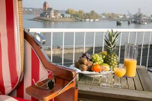 un tavolo con un cesto di frutta e bicchieri di succo d'arancia di Hotel AM ELBUFER ad Amburgo
