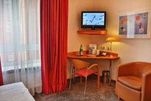 a room with a desk with a television and a chair at Hotel AM ELBUFER in Hamburg