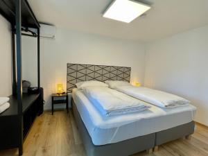 1 dormitorio con 1 cama grande con sábanas blancas en sHome TinyHouse Feldkirchen bei Graz - Self-Check-in, en Feldkirchen bei Graz