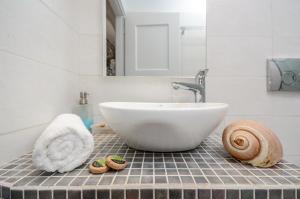 ein Badezimmer mit einem weißen Waschbecken und einem Spiegel in der Unterkunft Victoria Studios & Apartments in Mikri Vigla