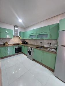 uma cozinha com armários verdes e uma máquina de lavar roupa em Très bel appart climatisé proche de la plage em Agadir