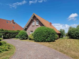 uma casa de tijolos com um telhado de gambrel e uma entrada em Am Sommerdeich em Norden