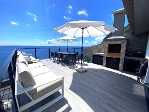 una terrazza in legno con tavolo e ombrellone di Ocean Front a Paul do Mar