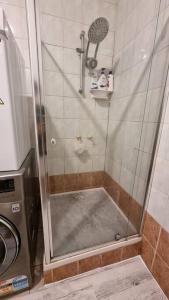 a shower with a glass door next to a washing machine at Comfortable 3 bebrooms old home with parking in Sunshine