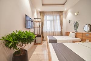 a hotel room with two beds and a potted plant at Bin Bin Hotel 2 - Near Him Lam D7 in Ho Chi Minh City
