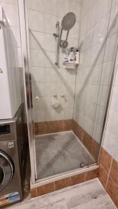 a shower with a glass door next to a washing machine at Comfortable 3 bebrooms old home with parking in Sunshine