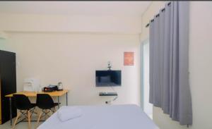 a bedroom with a bed and a desk and a tv at Apartment Bogorienze in Bogor