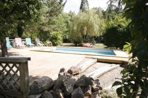 een zwembad in een tuin met een houten terras bij Gîte La Réserve avec Jardin et Piscine in Ingersheim