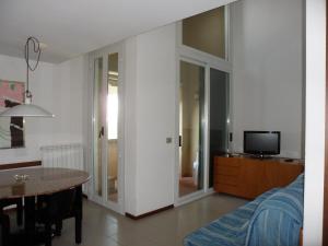 ein Wohnzimmer mit einem Sofa, einem Tisch und einem TV in der Unterkunft Appartamento 109 - Multiproprietà I Boboli BC in Punta Ala