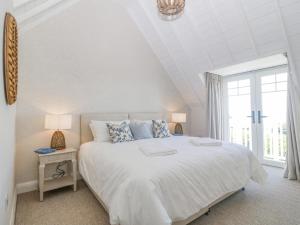a white bedroom with a large bed and a window at Haul A Gwynt in Criccieth