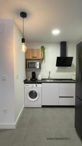 a kitchen with a washing machine and a microwave at Urbanlux Belmonte Suite in Albacete