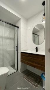 y baño con ducha, aseo y espejo. en Urbanlux Belmonte Suite en Albacete