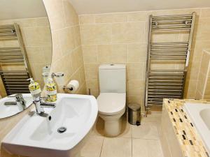 a bathroom with a toilet and a sink and a tub at Ilkley Central Penthouse in Ilkley