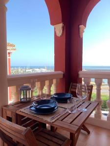 uma mesa de madeira com pratos e copos de vinho numa varanda em Hispalis Mazagón Beach 303 em Mazagón