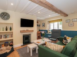 a living room with a green couch and a fireplace at Holly Cottage in Yeovil