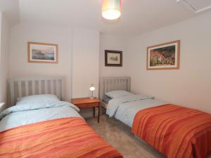 1 dormitorio con 2 camas y mesa con lámpara en Holly Cottage en Yeovil