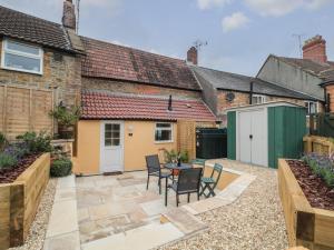 un patio en una casa con mesa y sillas en Holly Cottage en Yeovil