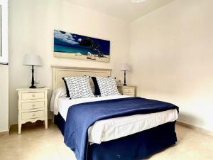 um quarto com uma cama com um cobertor azul e duas mesas de cabeceira em Hispalis Mazagón Beach 303 em Mazagón