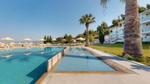 a large swimming pool with palm trees and a building at Acrotel Lilyann Boutique Hotel in Elia
