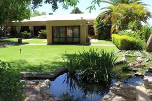 a house with a pond in front of a yard at Peaceful Garden Cottage in Kakamas