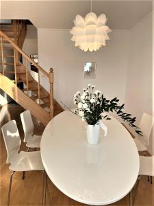 a white dining room table with white chairs and a vase of flowers at Apartamenty Studio W Ustce - 120 m2 - 200 m od plaży Mickiewicza 2, in Ustka