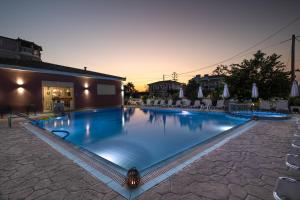 a large swimming pool with chairs and a building at Dinos Hotel in Tsilivi