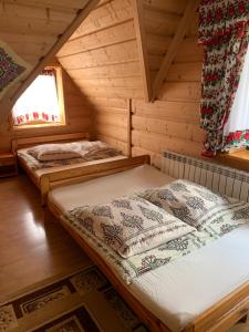 two beds in a log cabin with a window at Pokoje u Magdusi przy termach in Witów
