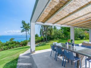 eine Terrasse mit einem Tisch, Stühlen und Meerblick in der Unterkunft Dilean luxury villa in Vourvourou