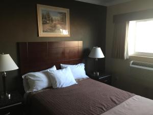 a bedroom with a bed with white pillows and a window at Seaside Motel in Redondo Beach