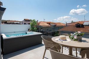 eine Terrasse mit einem Tisch und einer Badewanne auf einem Balkon in der Unterkunft Evitel Luxury Living in Chaniotis