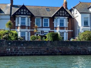 a large brick house next to a body of water at A unique and spacious river front property in Shaldon