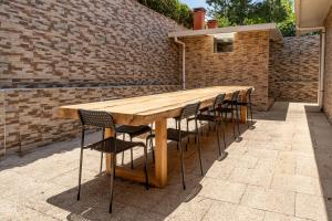 a long wooden table and chairs in front of a brick wall at Lisbon Surf Hostel in Carcavelos