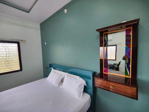 a bedroom with a white bed and a mirror at Srinivasa Homestay in Hampi