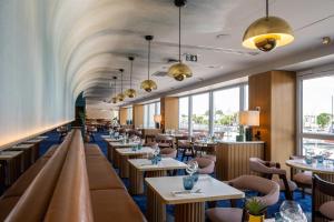 un restaurant avec des tables, des chaises et des fenêtres dans l'établissement Mercure La Rochelle Vieux Port, à La Rochelle