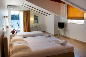 una camera d'albergo con due letti e una televisione di Akrogiali Studios a Nydri