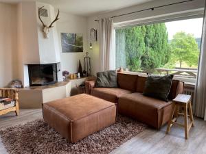 ein Wohnzimmer mit einem braunen Sofa und einem großen Fenster in der Unterkunft Apartment Haus Aktiv Garten in Winterberg