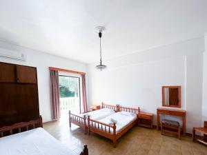 1 dormitorio con 2 camas y ventana en Stamiris Beach Hotel, en Vasilikos