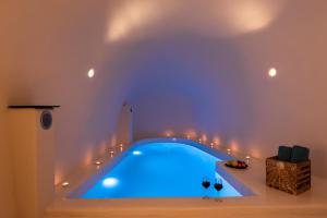een blauw zwembad in een kamer met wijnglazen bij Twenty One Suites in Oia