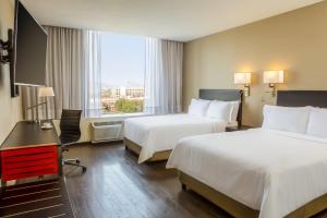 a hotel room with two beds and a desk and a window at Fiesta Inn Centro Historico in Mexico City