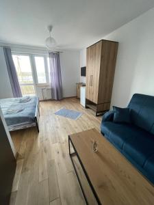 a living room with a blue couch and a bed at Port Jabłonka in Nidzica