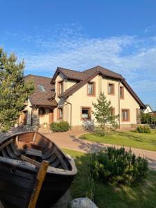 a house with a boat in front of it at Zielone Miejsce - w otoczeniu natury, z balią z jacuzzi opalaną drewnem in Karwia