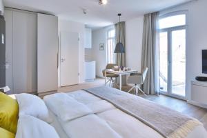 a white bedroom with a large bed and a table at Lüttjeod Apartmentvilla Lüttjeod Apartmentvilla 14 in Langeoog