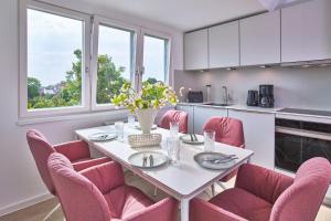 a kitchen with a white table and pink chairs at Lüttjeod Apartmentvilla Lüttjeod Apartmentvilla 16 in Langeoog