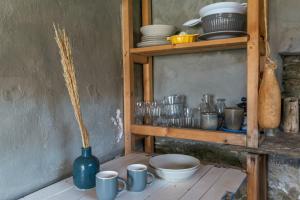 a shelf with dishes and a vase on a table at The Fishermans Experience Tinos in Platiá