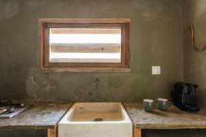 a kitchen with a sink and a window at The Fishermans Experience Tinos in Platiá