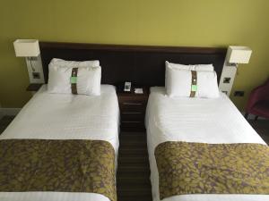 two beds sitting next to each other in a hotel room at Holiday Inn Huntingdon Racecourse, an IHG Hotel in Huntingdon