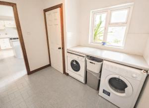 a laundry room with a washing machine and a window at Lark Rise Holiday Home Glenbeigh in Glenbeigh