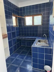 a blue tiled bathroom with a sink and a toilet at Puraran Surf Beach Resort in Baras