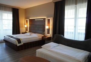 バート・フィルベルにあるシティ ホテル フランクフルト バート フィルベルのベッド2台とソファが備わるホテルルームです。